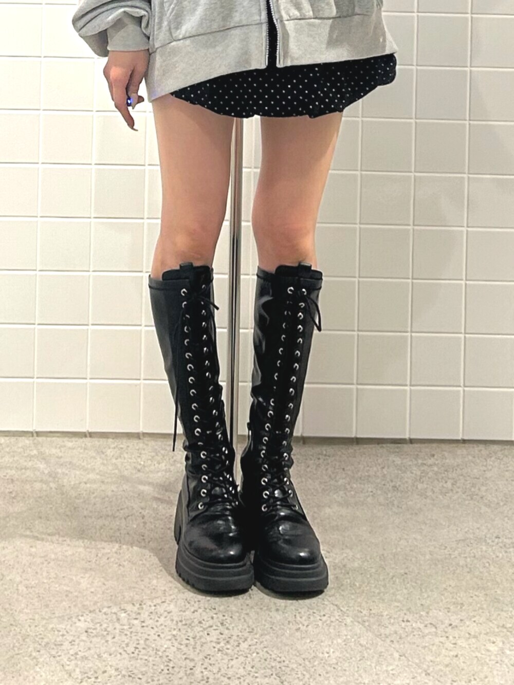 ブラック系のブーツ、グレー系のパーカー、ブラック系のスカートを着用したレディースの秋コーディネートの6枚目の写真