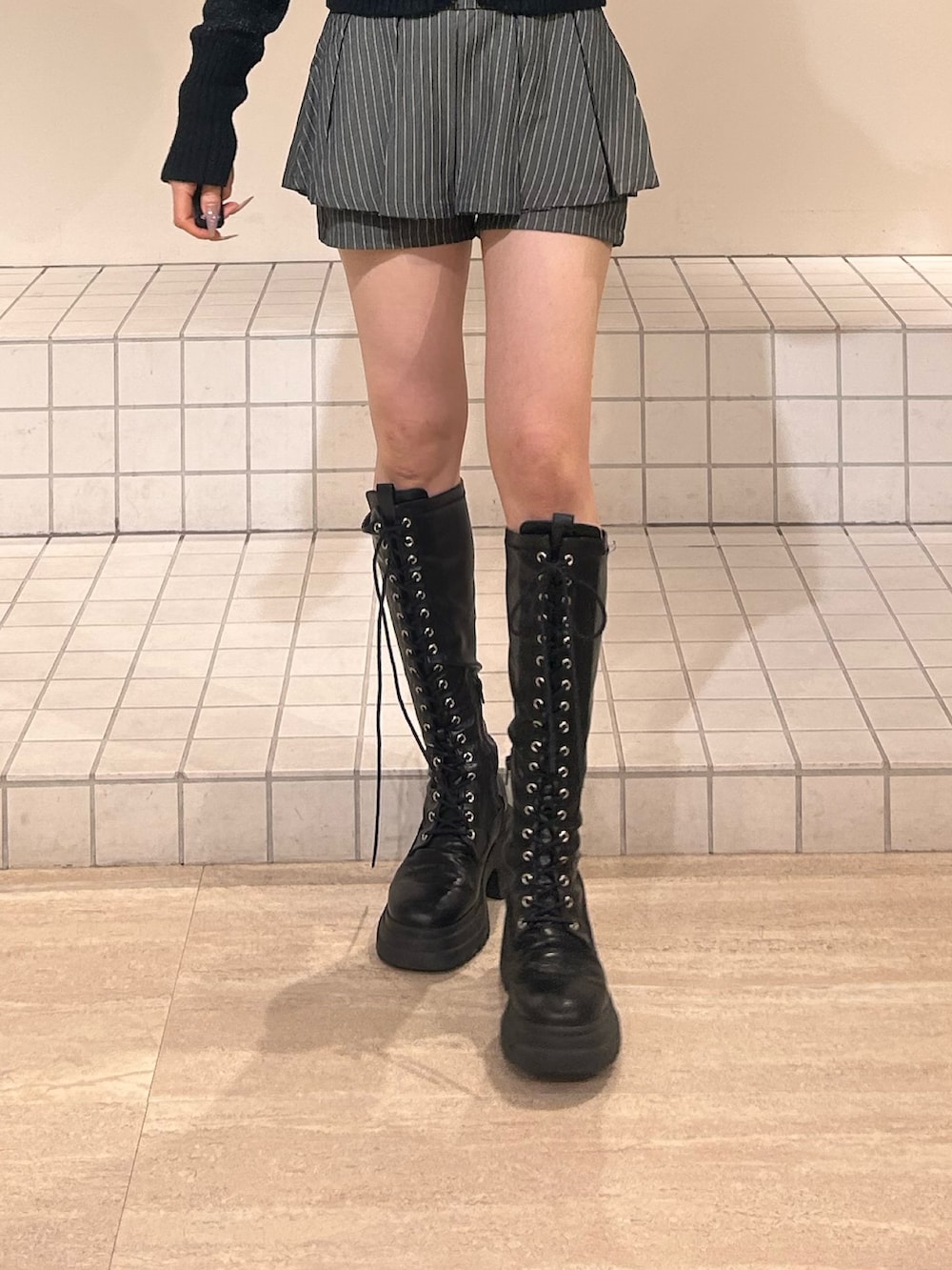 ブラック系のパーカー、グレー系のスカート、ブラック系のブーツを着用したレディースの冬コーディネートの6枚目の写真