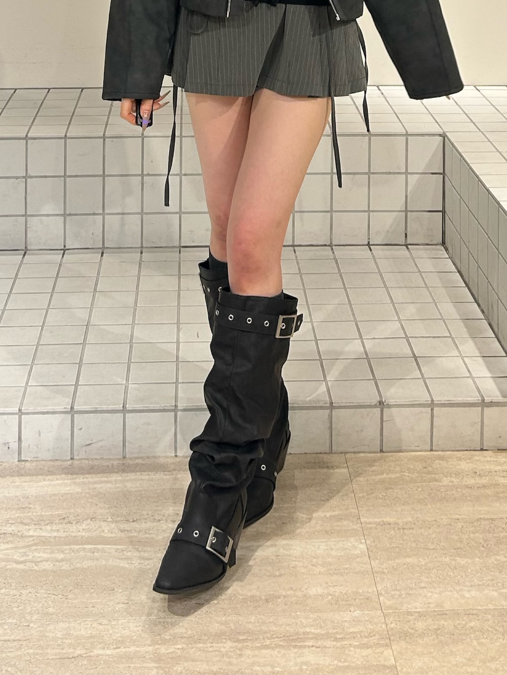 ブラック系のブーツ、グレー系のスカート、ブラック系のブルゾンを着用したレディースの冬コーディネートの8枚目の写真