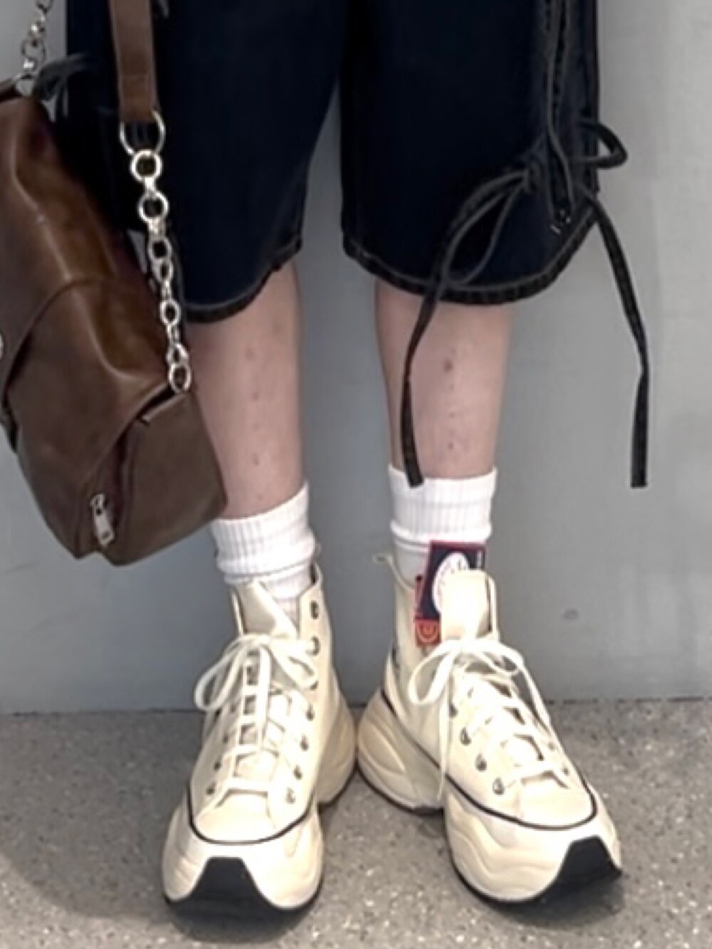 ブラウン系のキャミソール、ブラック系のデニムパンツ、ホワイト系のスニーカーを着用したレディースの春コーディネートの7枚目の写真