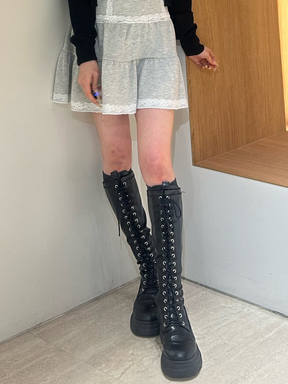 グレー系のワンピース、ブラック系のブーツ、ブラック系のカーディガン/ボレロを着用したレディースの春コーディネートの6枚目の写真