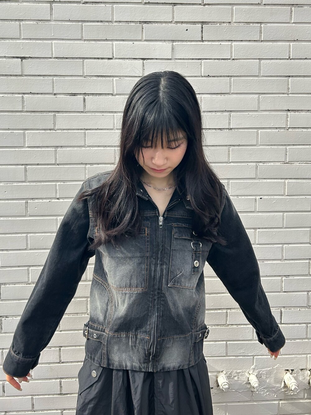 ブラック系のデニムジャケット、ブラック系のスカートを着用したレディースの冬コーディネートの2枚目の写真