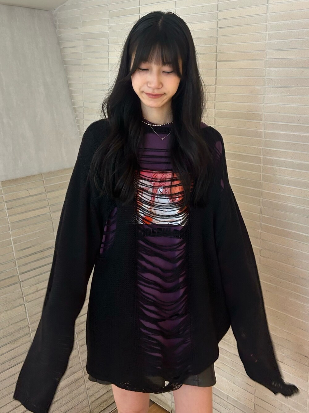 ブラック系のニット/セーター、パープル系のTシャツ/カットソー、ブラック系のスカートを着用したレディースの秋コーディネートの4枚目の写真