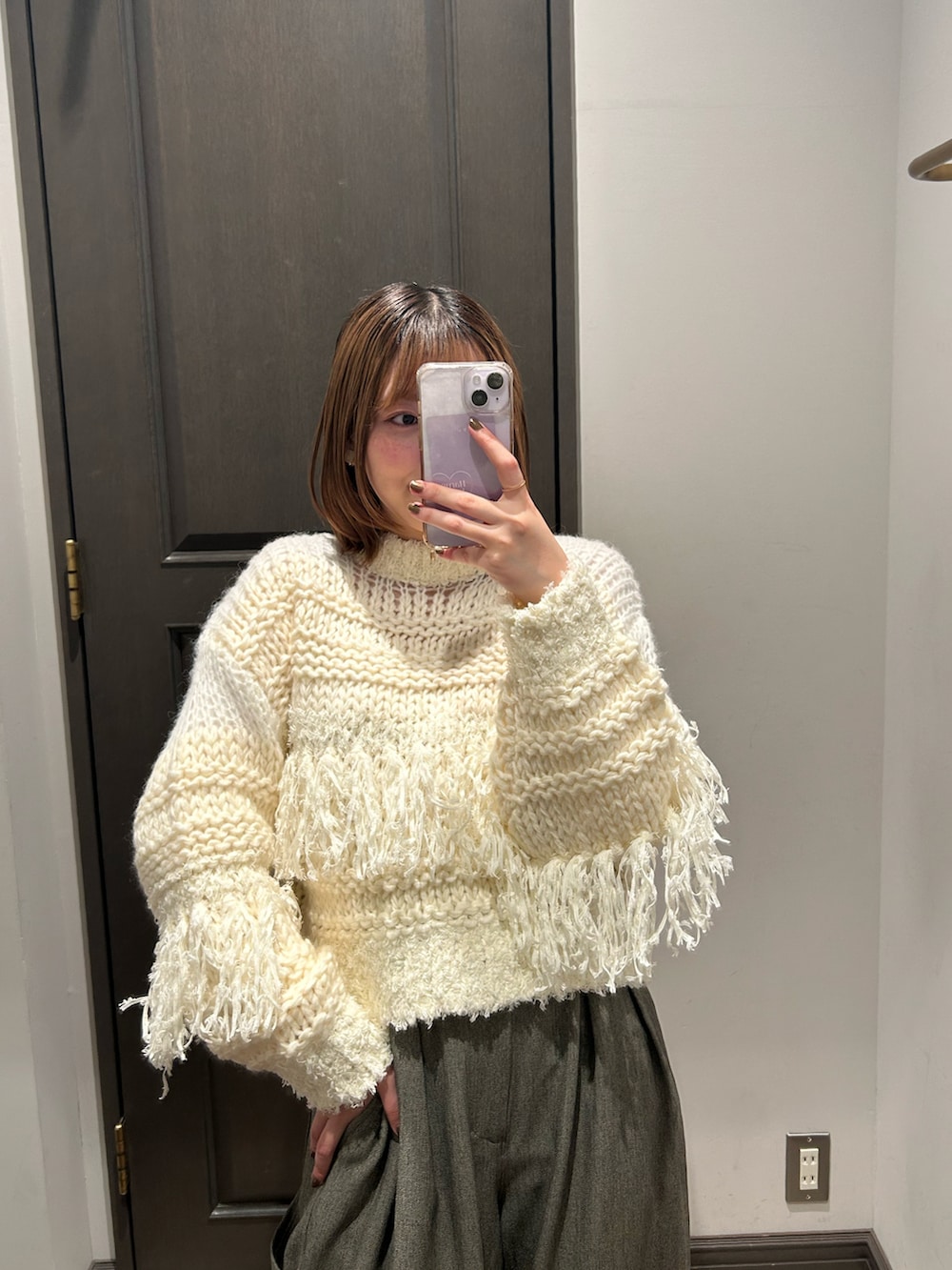 ホワイト系のニット/セーター、グレー系のスラックス、ブラック系のブーツを着用したレディースの冬コーディネートの2枚目の写真