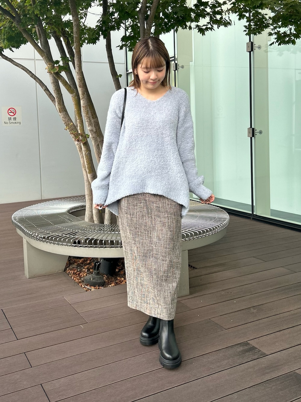 ブルー系のニット/セーター、ベージュ系のノーカラーコート、ブラウン系のスカートを着用したレディースの冬コーディネートの2枚目の写真