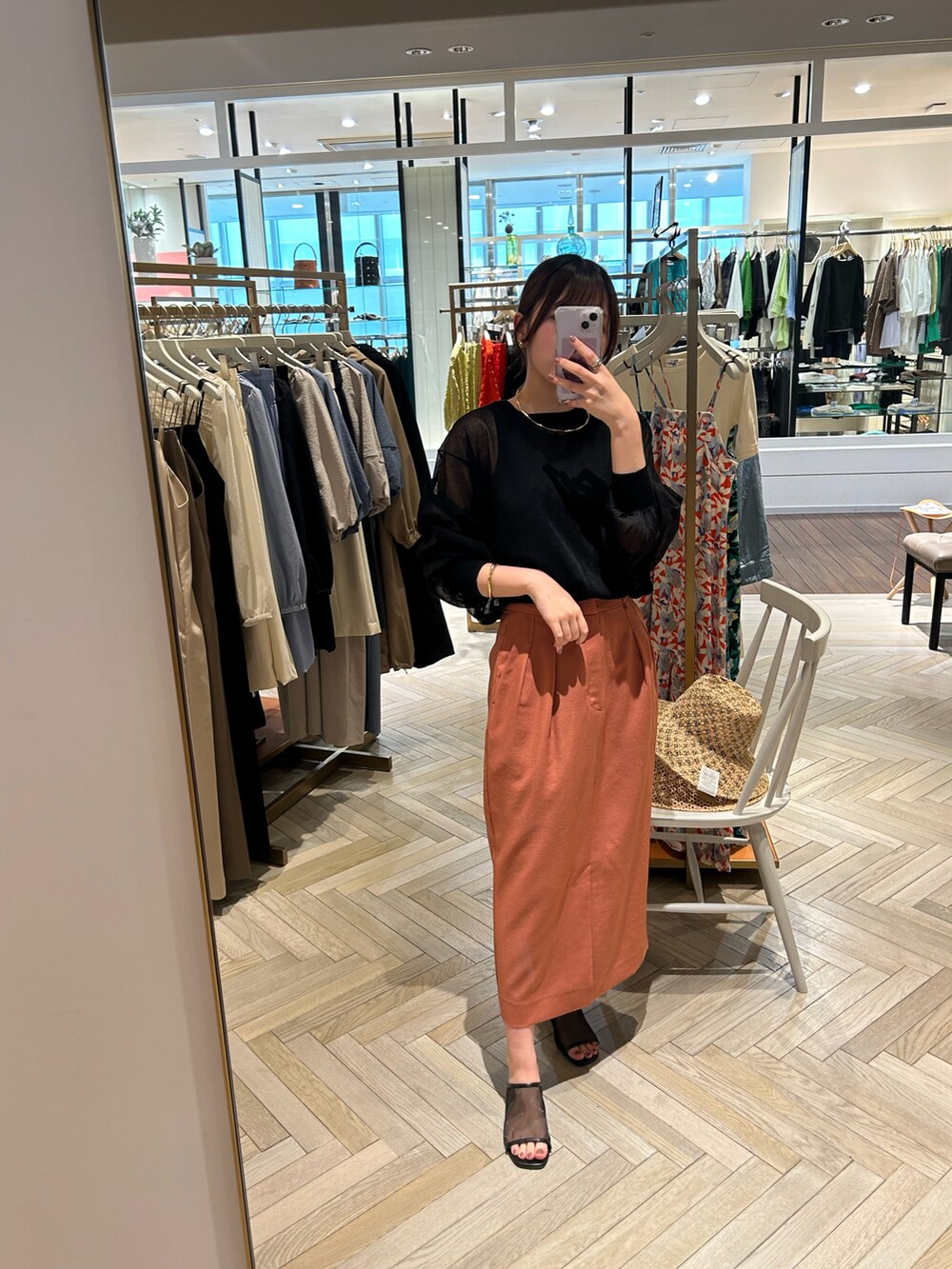 ブラック系のニット/セーター、ブラック系のタンクトップ、オレンジ系のスカートを着用したレディースの春コーディネートの2枚目の写真