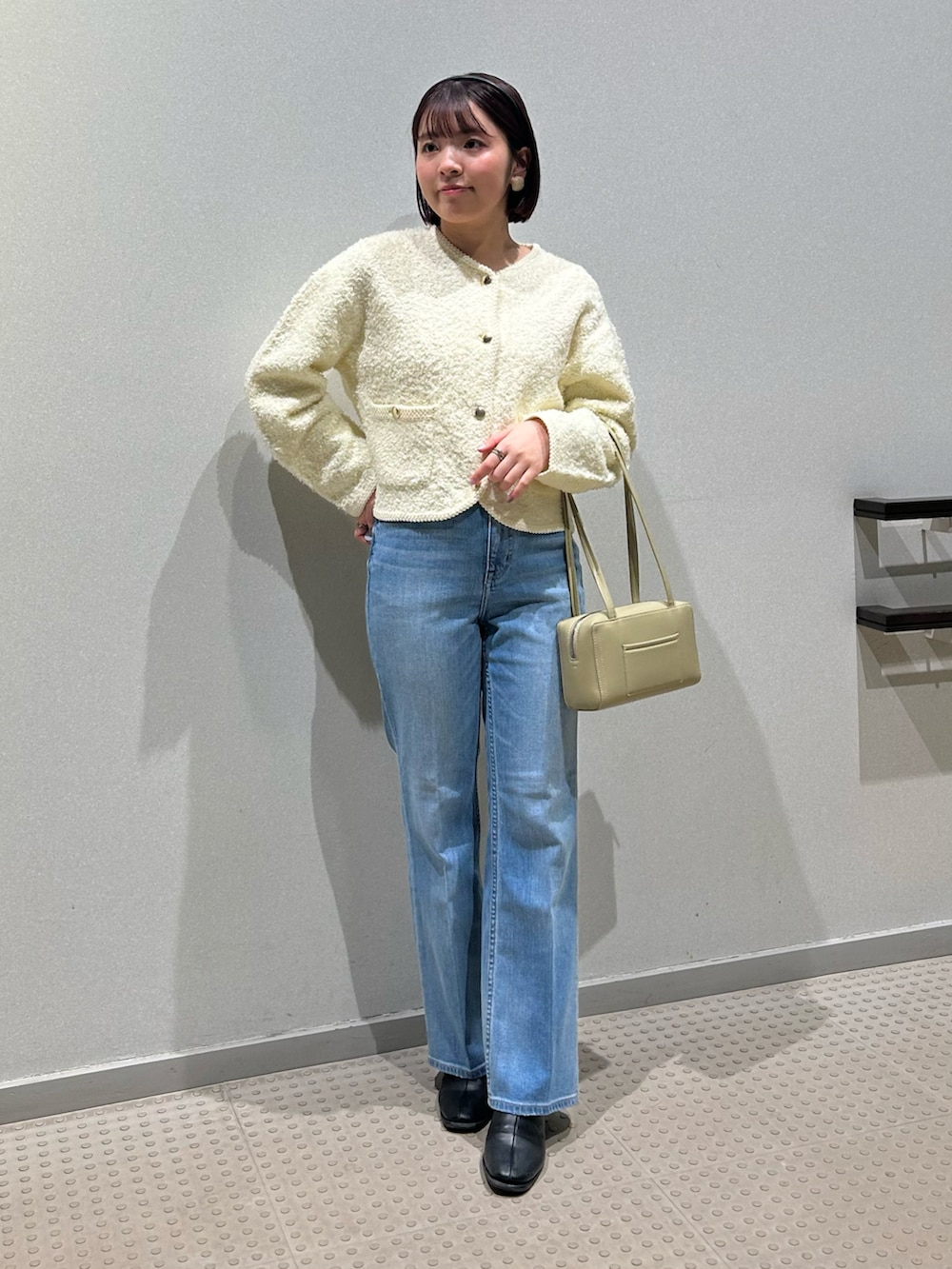 ホワイト系のノーカラージャケット、ブルー系のデニムパンツ、ブラック系のブーツを着用したレディースの春コーディネートの2枚目の写真