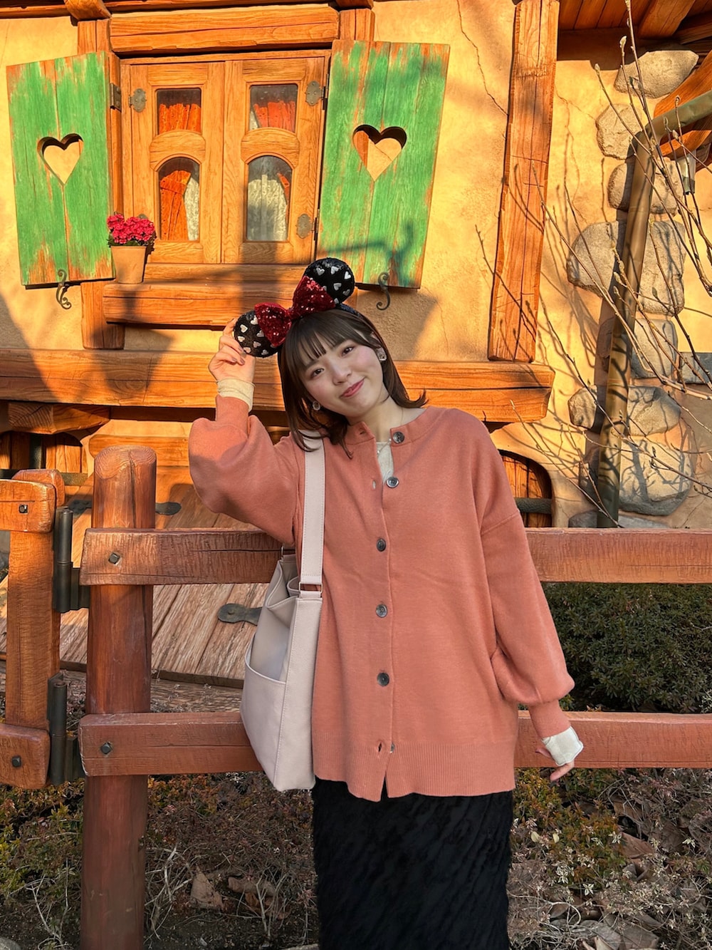 オレンジ系のカーディガン/ボレロ、ベージュ系のTシャツ/カットソー、ブラック系のスカートを着用したレディースの春コーディネートの3枚目の写真