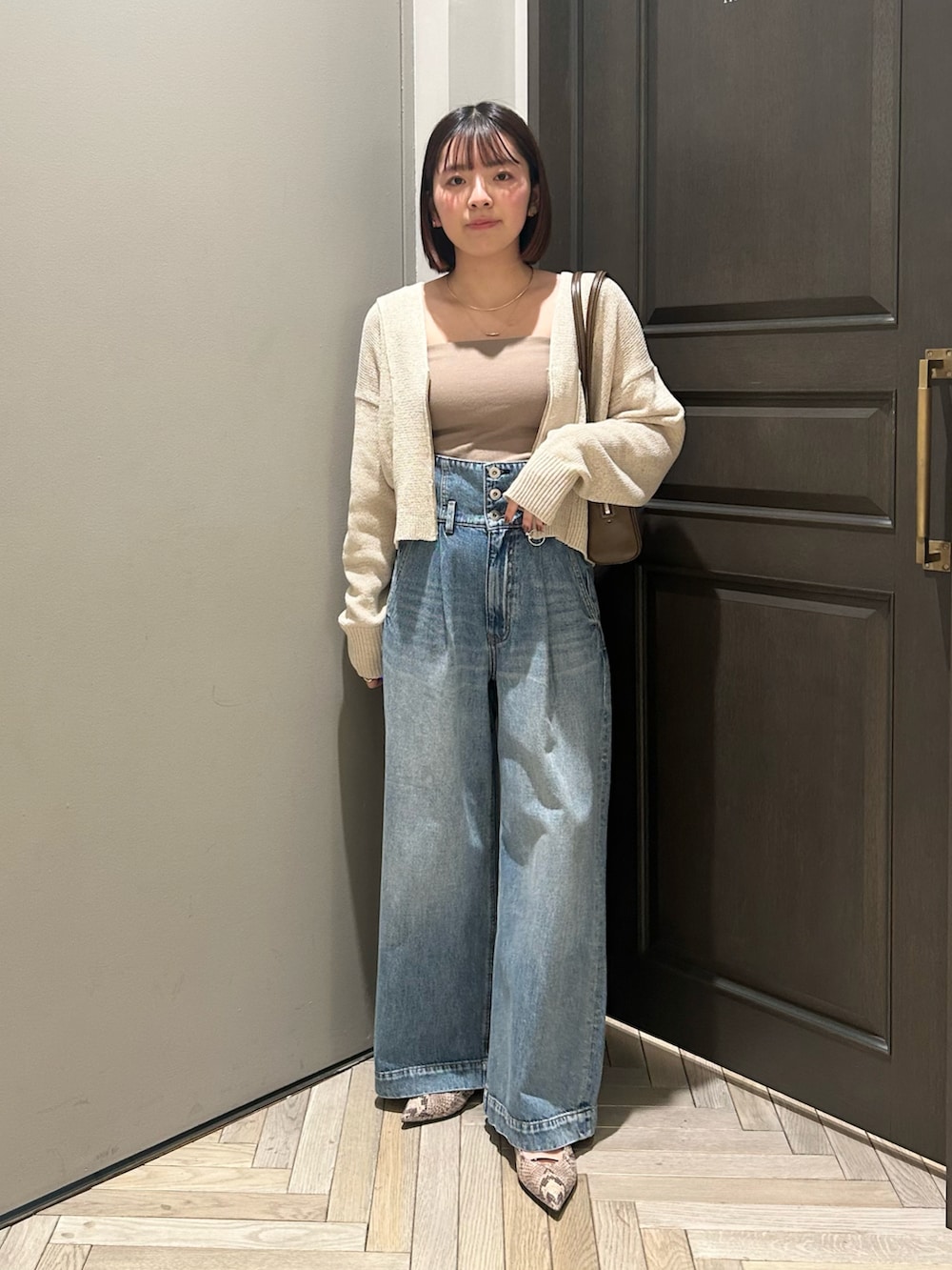 ベージュ系のカーディガン/ボレロ、ブルー系のデニムパンツ、ブラウン系のショルダーバッグを着用したレディースの春コーディネートの2枚目の写真