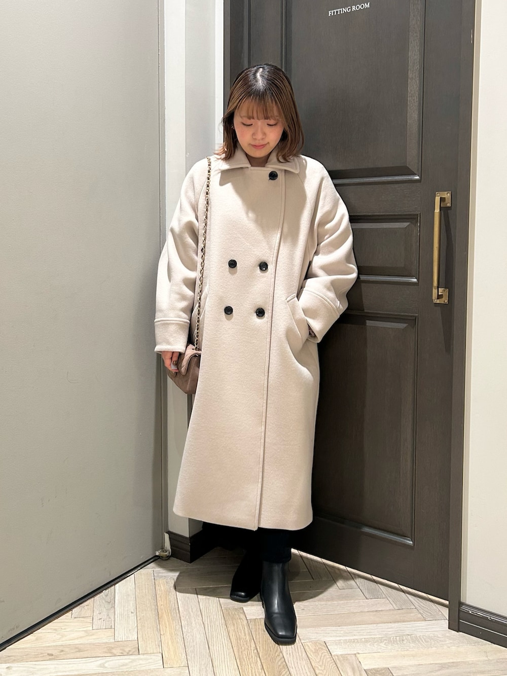 ブラウン系のニット/セーター、ブラック系のスカート、ベージュ系のチェスターコートを着用したレディースの冬コーディネートの3枚目の写真