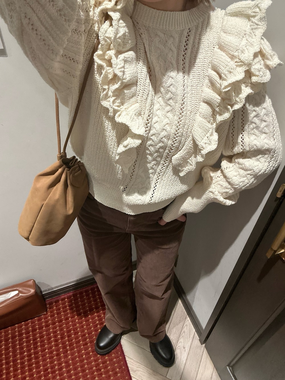 ホワイト系のニット/セーター、ブラック系のブーツ、ブラウン系のショルダーバッグを着用したレディースの冬コーディネートの2枚目の写真