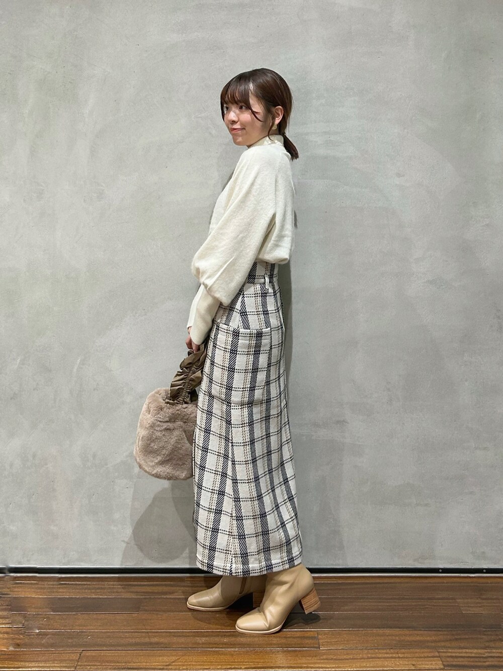 ホワイト系のニット/セーター、ベージュ系のハンドバッグ、ベージュ系のブーツを着用したレディースの秋コーディネートの2枚目の写真