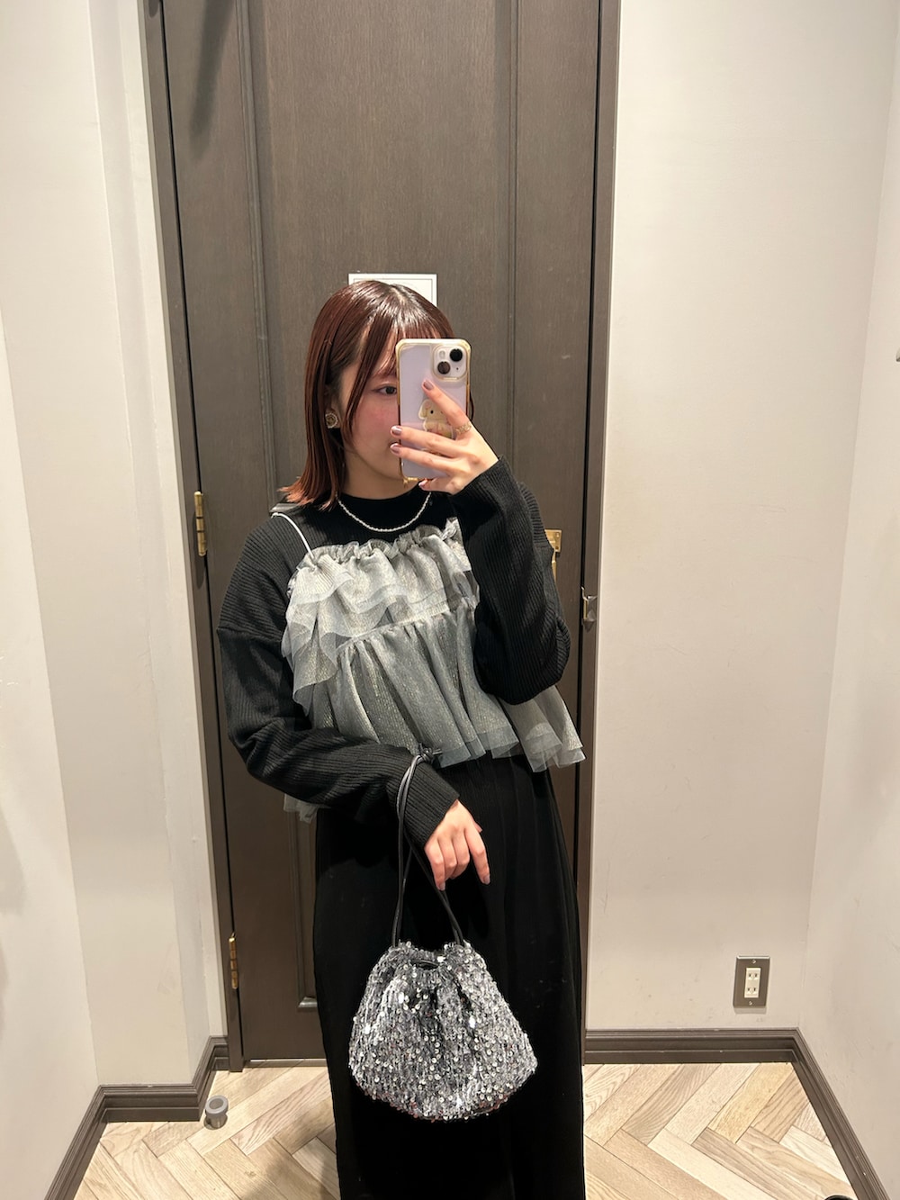 シルバー系のショルダーバッグ、ブラック系のワンピース、ベージュ系のブーツを着用したレディースの冬コーディネートの3枚目の写真