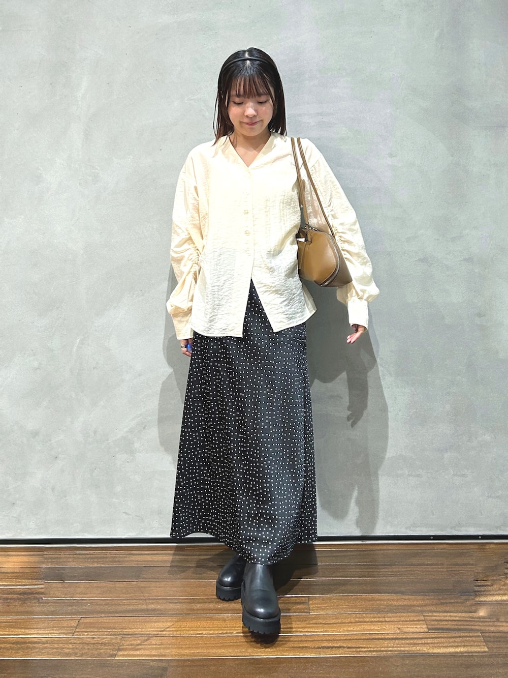 ベージュ系のシャツ/ブラウス、ブラック系のスカート、ブラック系のブーツを着用したレディースの秋コーディネートの2枚目の写真