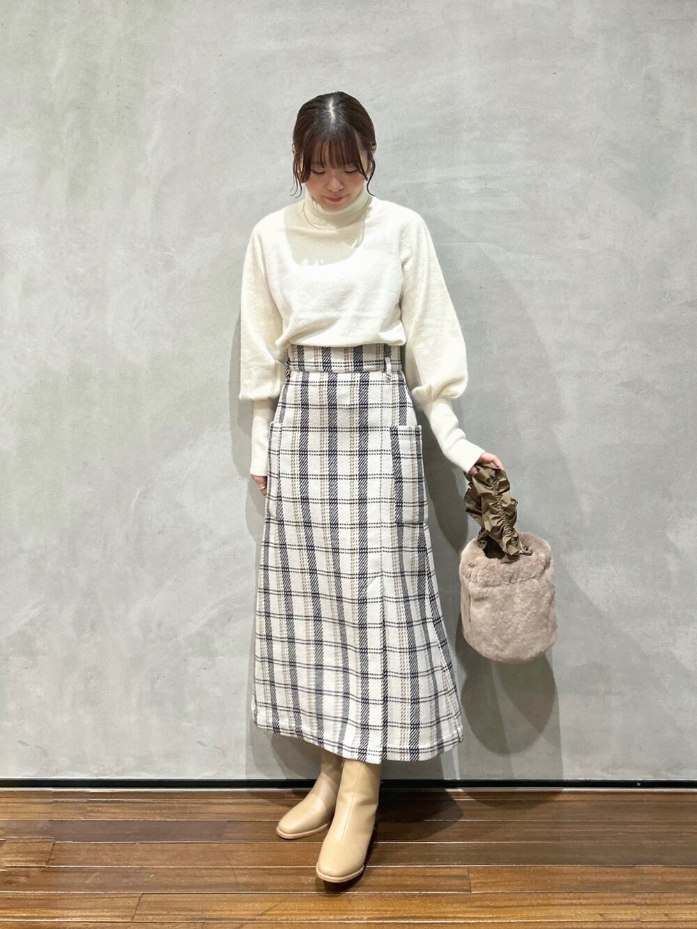 ホワイト系のニット/セーター、ベージュ系のハンドバッグ、ベージュ系のブーツを着用したレディースの秋コーディネートの3枚目の写真