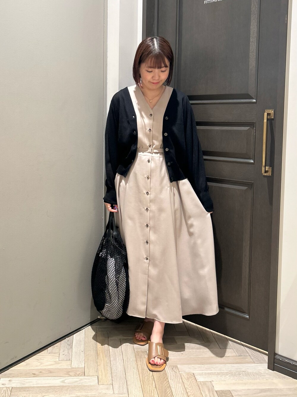 ベージュ系のワンピース、ブラック系のニット/セーター、ベージュ系のサンダルを着用したレディースの秋コーディネートの2枚目の写真