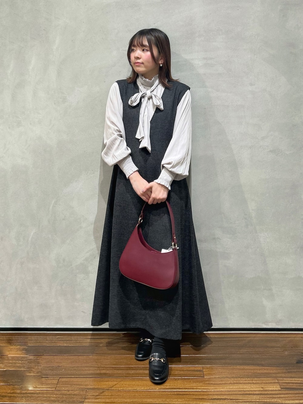 グレー系のシャツ/ブラウス、グレー系のジャンパースカート、レッド系のショルダーバッグを着用したレディースの冬コーディネートの2枚目の写真