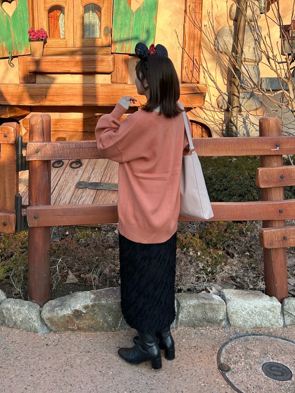 オレンジ系のカーディガン/ボレロ、ベージュ系のTシャツ/カットソー、ブラック系のスカートを着用したレディースの春コーディネートの2枚目の写真