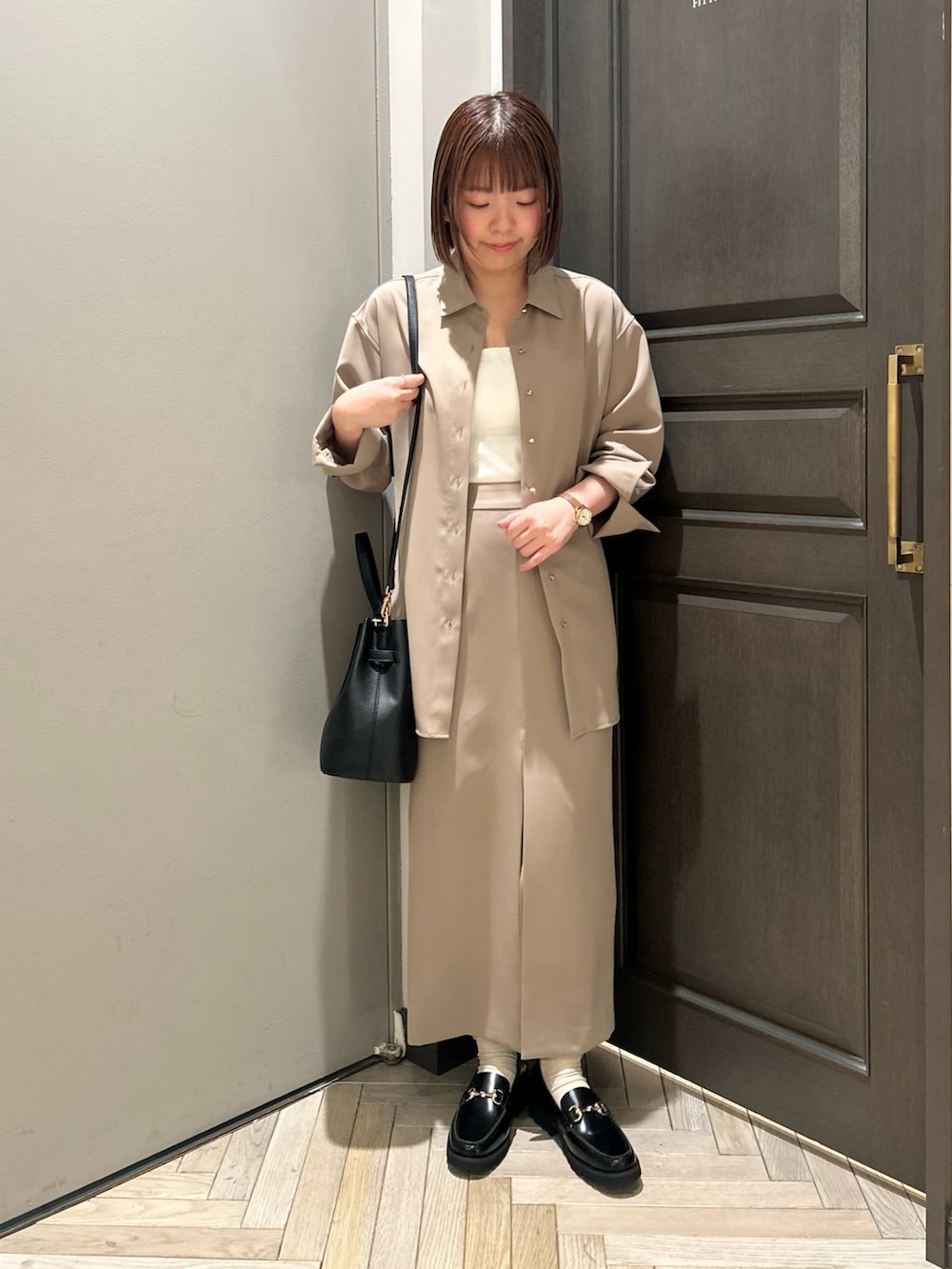 ベージュ系のシャツ/ブラウス、ベージュ系のスカート、ブラック系のショルダーバッグを着用したレディースの春コーディネートの2枚目の写真