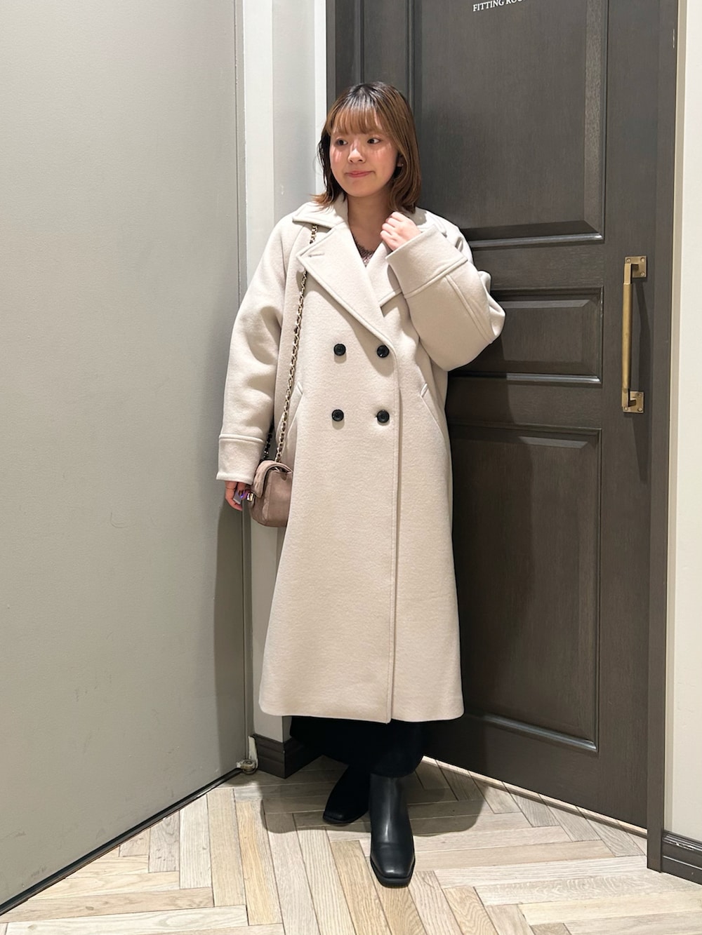 ブラウン系のニット/セーター、ブラック系のスカート、ベージュ系のチェスターコートを着用したレディースの冬コーディネートの2枚目の写真