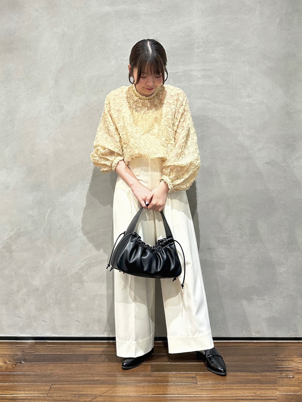イエロー系のシャツ/ブラウス、ホワイト系のその他パンツ、ブラック系のハンドバッグを着用したレディースの春コーディネートの2枚目の写真