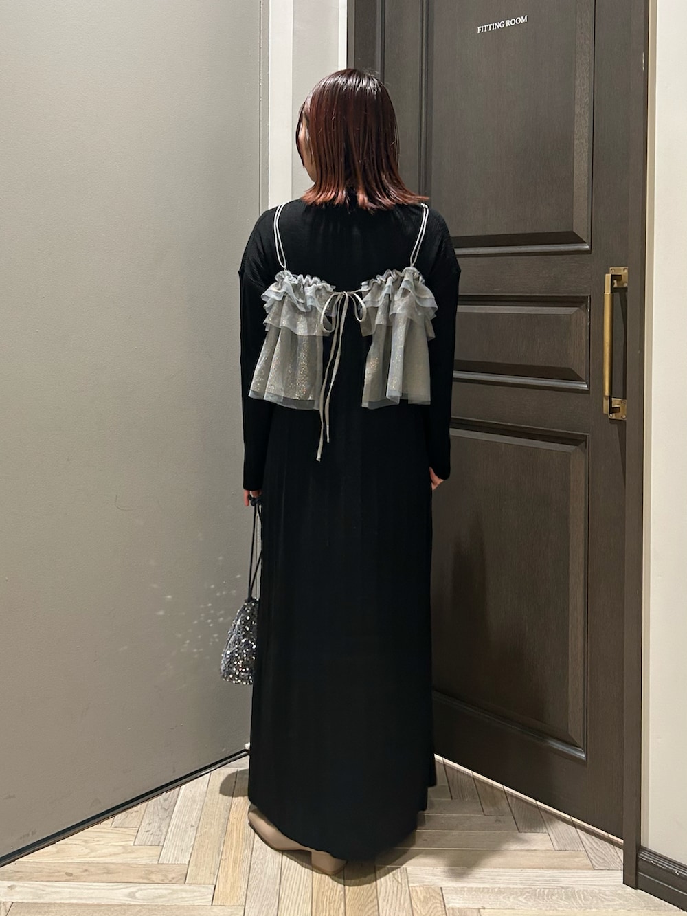 シルバー系のショルダーバッグ、ブラック系のワンピース、ベージュ系のブーツを着用したレディースの冬コーディネートの2枚目の写真