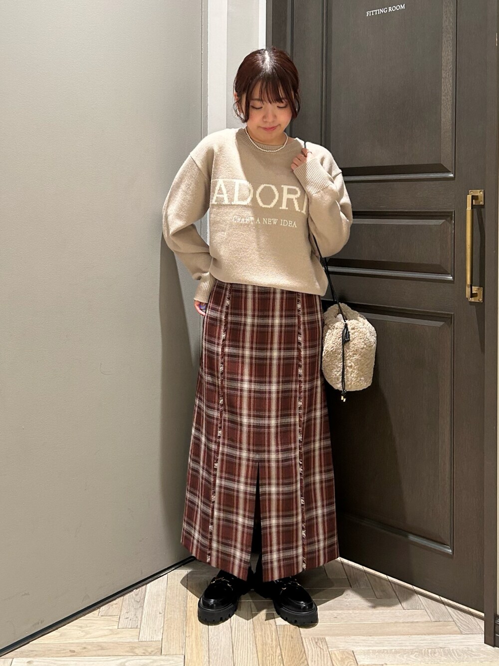 ベージュ系のニット/セーター、レッド系のスカート、ブラック系のローファーを着用したレディースの冬コーディネートの2枚目の写真