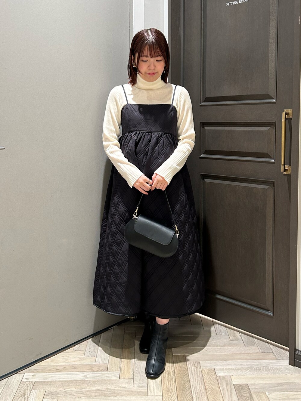 ブラック系のワンピース、ブラック系のブーツ、ホワイト系のニット/セーターを着用したレディースの秋コーディネートの2枚目の写真