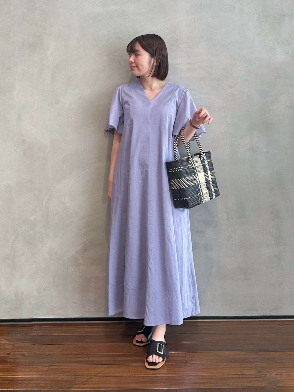 パープル系のワンピース、ブラック系のハンドバッグ、ブラック系のサンダルを着用したレディースの春コーディネートの2枚目の写真