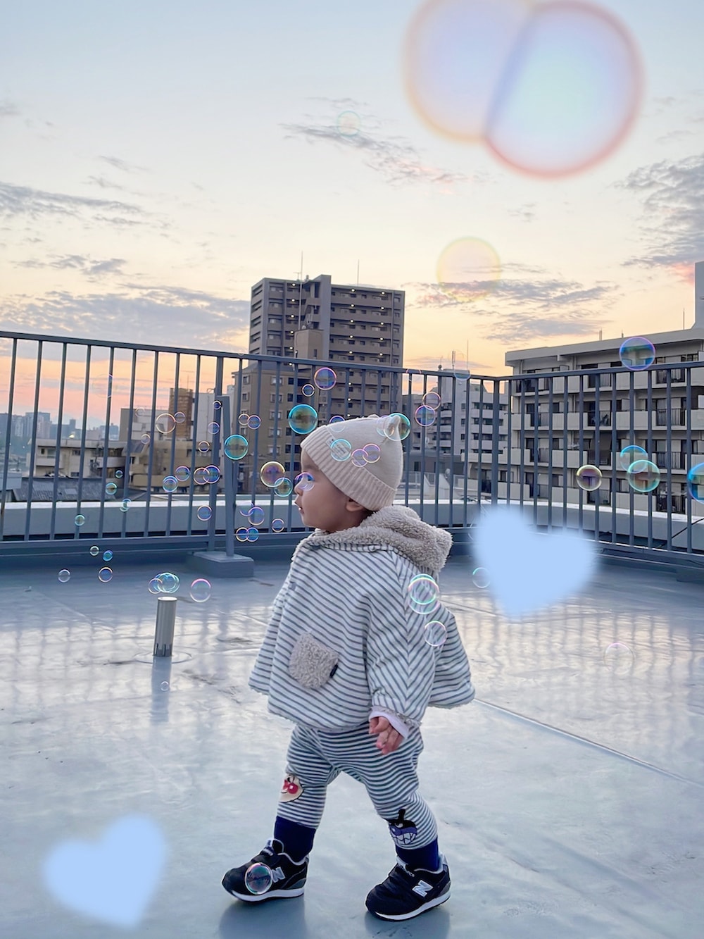 その他のポンチョ、ブラック系のスニーカー、ホワイト系のニットキャップ/ビーニーを着用したキッズの冬コーディネートの2枚目の写真