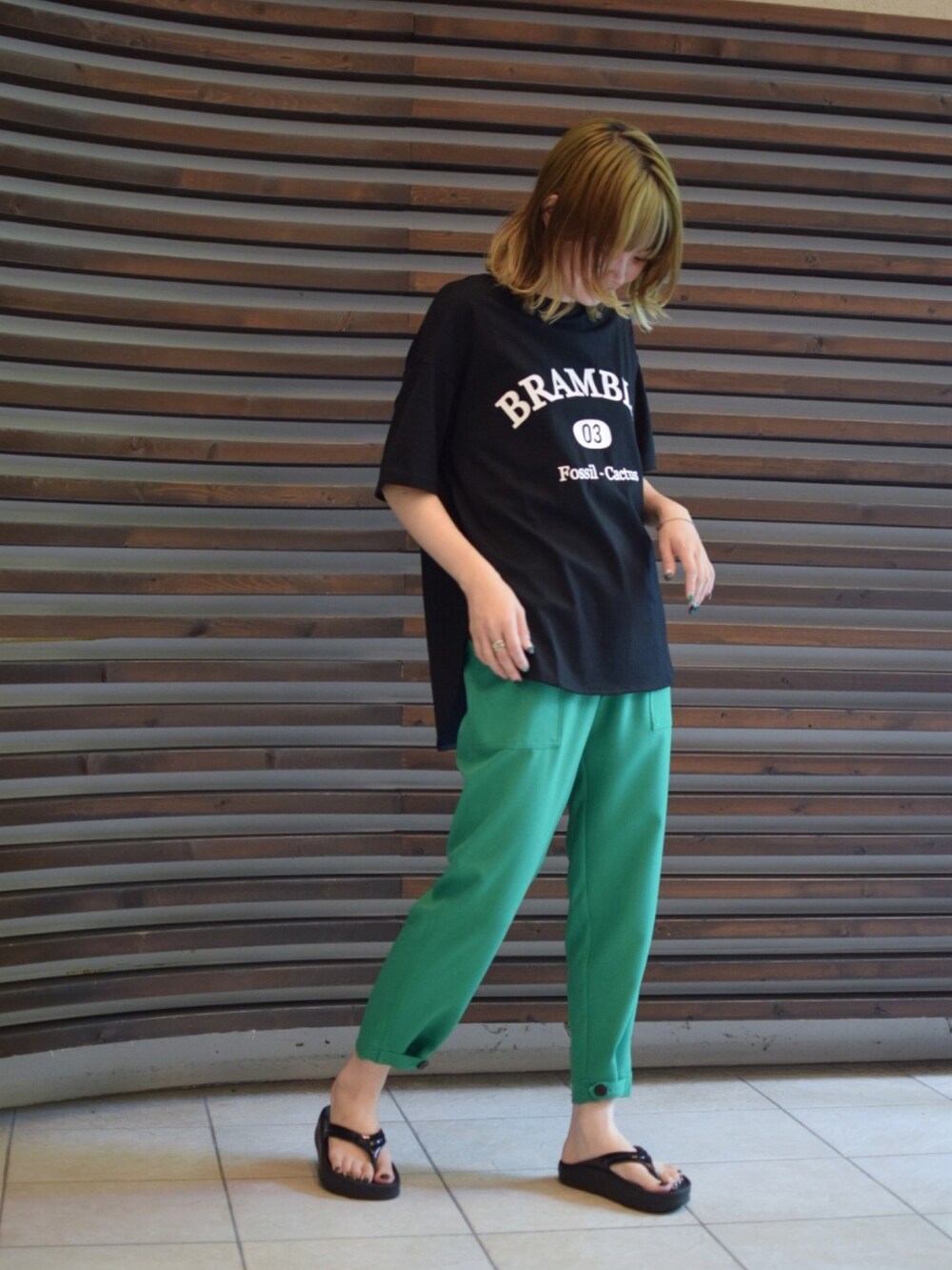 グリーン系のパンツ、ブラック系のTシャツ/カットソーを着用したレディースの夏コーディネートの2枚目の写真
