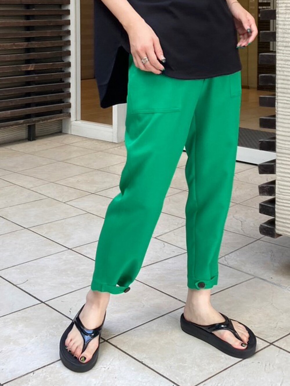 グリーン系のパンツ、ブラック系のTシャツ/カットソーを着用したレディースの夏コーディネートの3枚目の写真