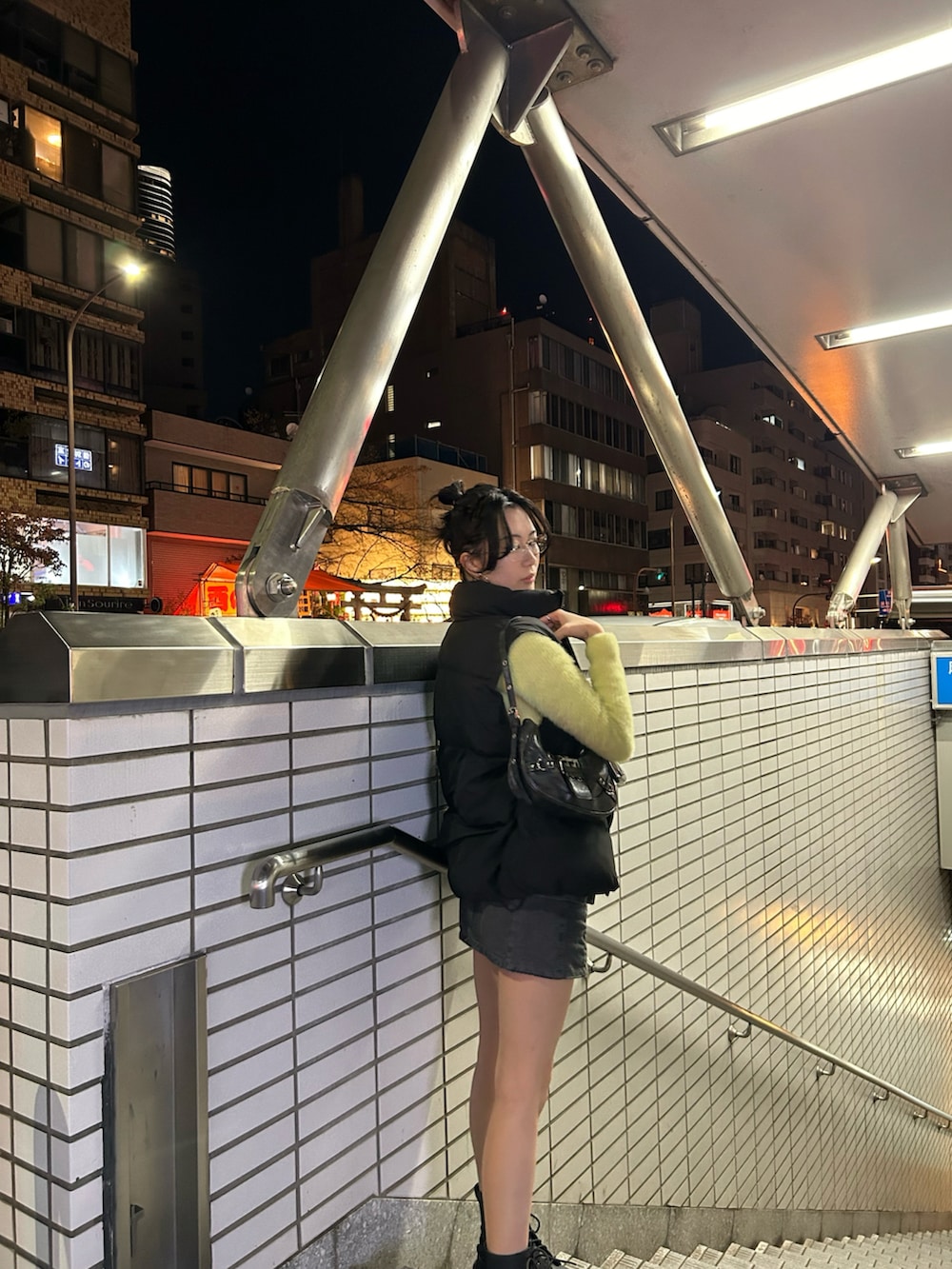 グリーン系のニット/セーター、グレー系のスカート、ブラック系のダウンベストを着用したレディースの秋コーディネートの4枚目の写真