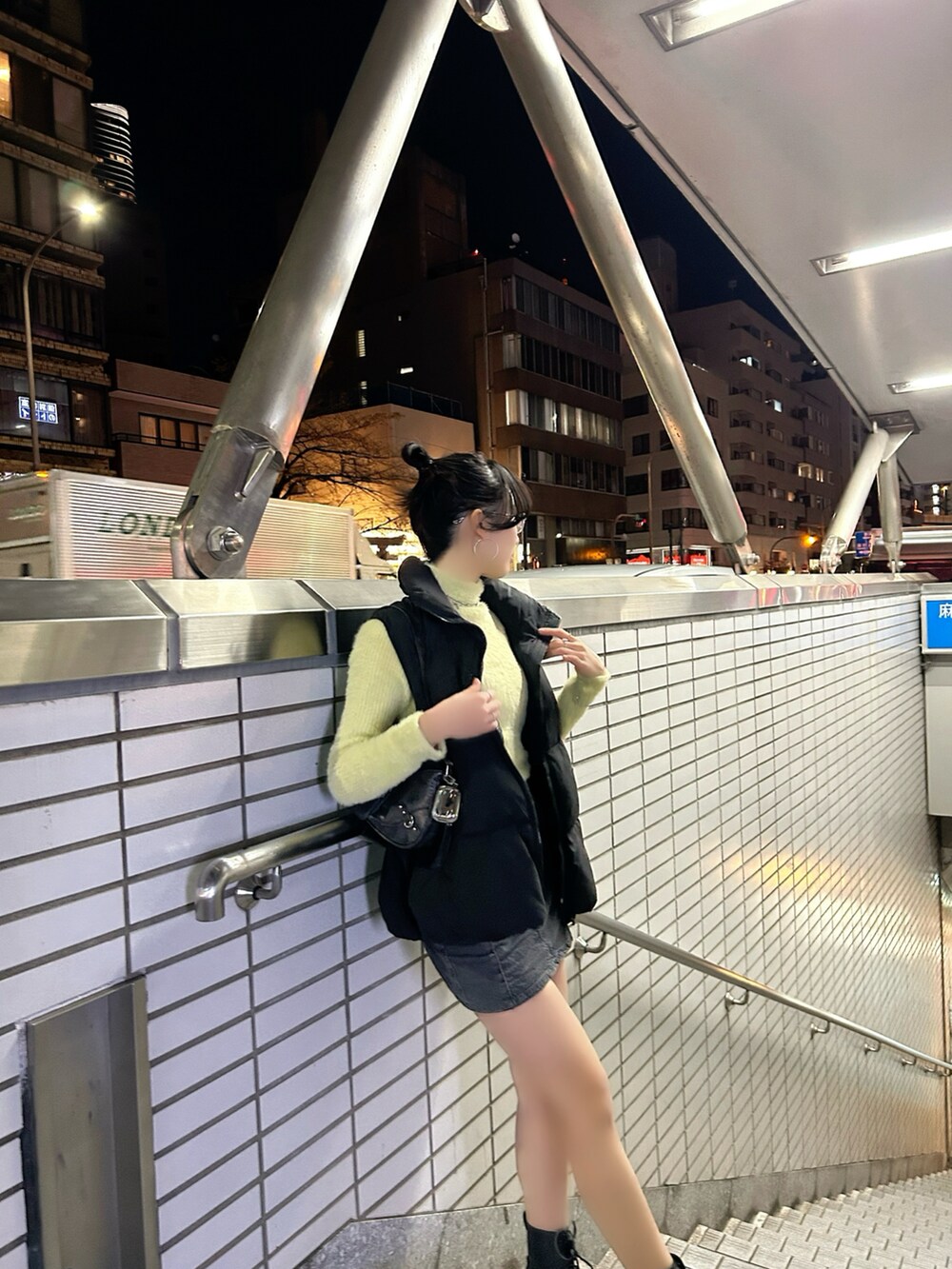 グリーン系のニット/セーター、グレー系のスカート、ブラック系のダウンベストを着用したレディースの秋コーディネートの3枚目の写真