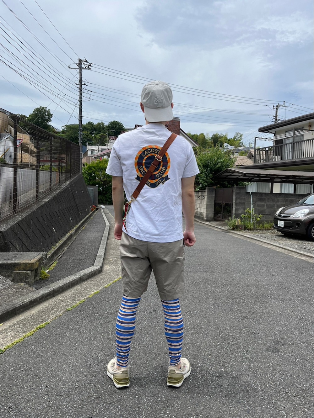 ホワイト系のTシャツ/カットソー、グリーン系のショルダーバッグ、ベージュ系のパンツを着用したメンズの春コーディネートの2枚目の写真