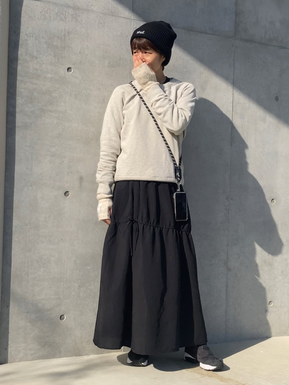 ブラック系のスカート、ブラック系のスニーカー、ベージュ系のスウェットを着用したレディースの秋コーディネートの2枚目の写真
