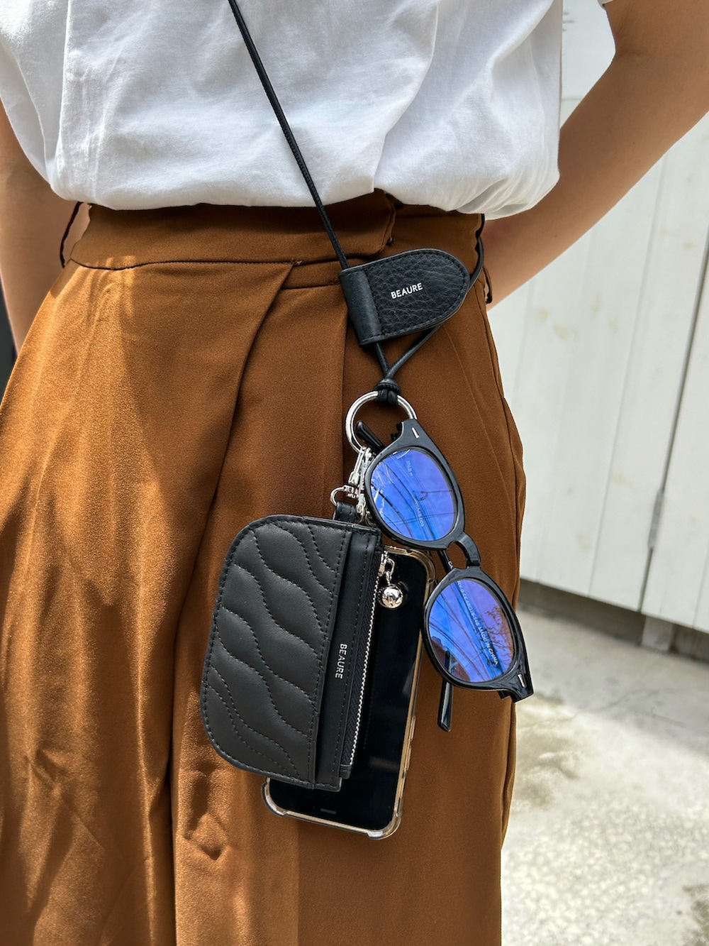 ホワイト系のサンダル、ブラック系のスマホグッズ、ブラック系のパスケースを着用したレディースの春コーディネートの2枚目の写真