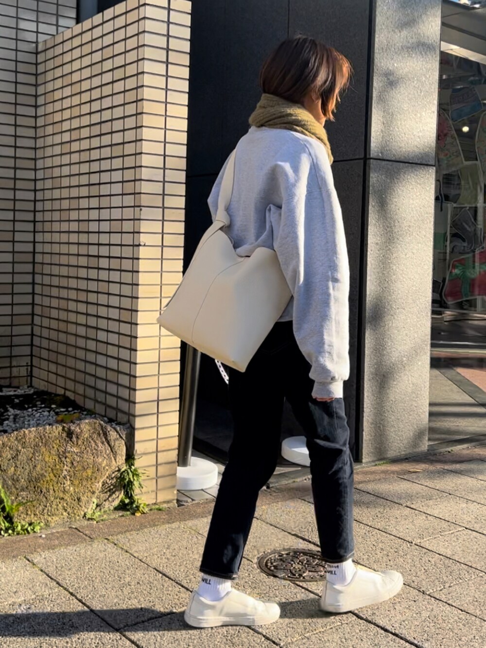ホワイト系のショルダーバッグ、グレー系のスウェット、ブルー系のデニムパンツを着用したレディースの冬コーディネートの2枚目の写真