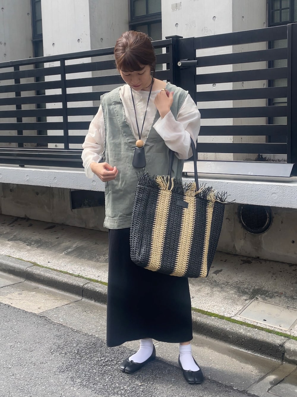 ブラック系のトートバッグ、ベージュ系のTシャツ/カットソー、グリーン系のベストを着用したレディースの春コーディネートの2枚目の写真