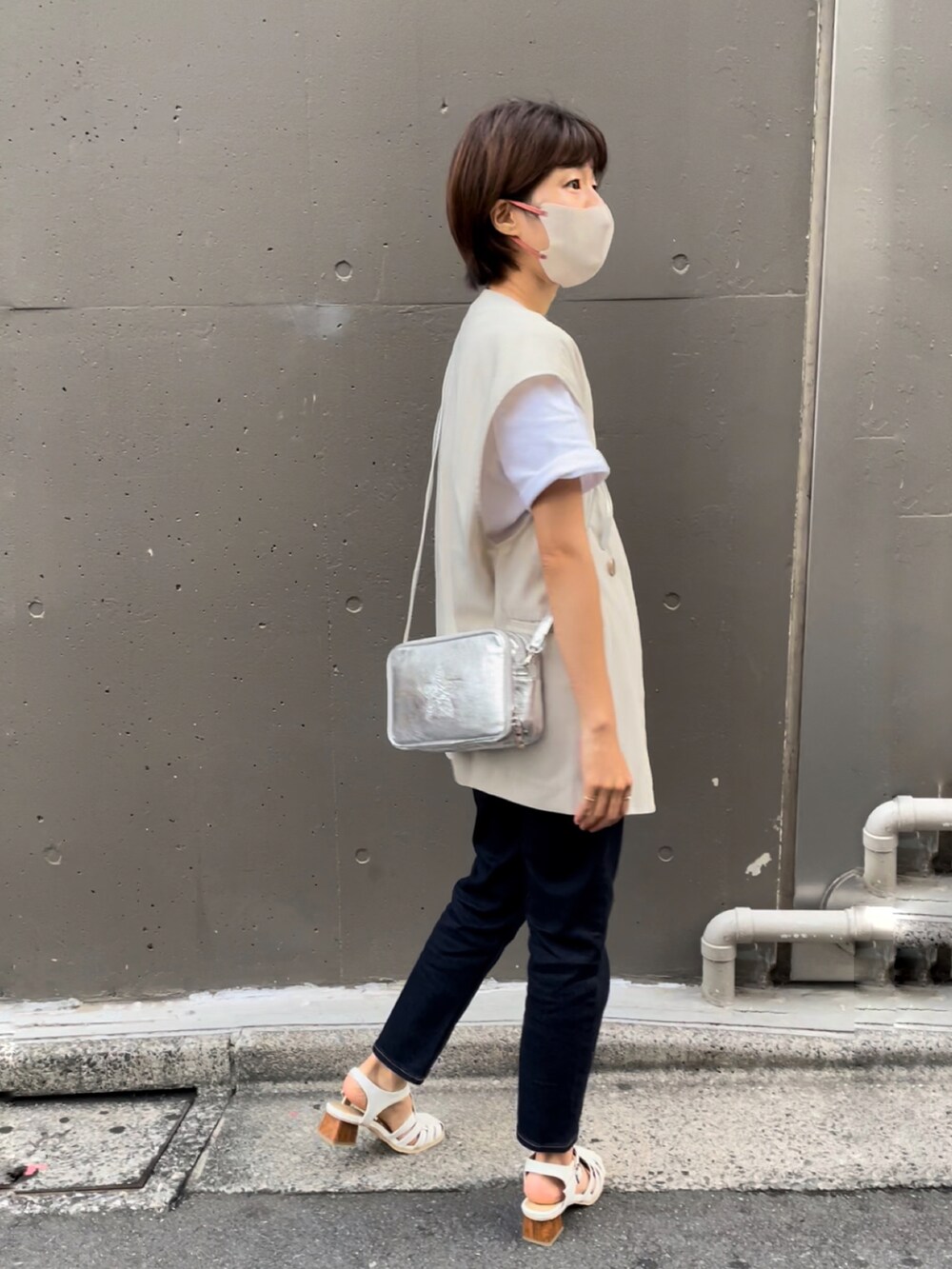 シルバー系のショルダーバッグ、ホワイト系のベスト、ホワイト系のTシャツ/カットソーを着用したレディースの夏コーディネートの2枚目の写真