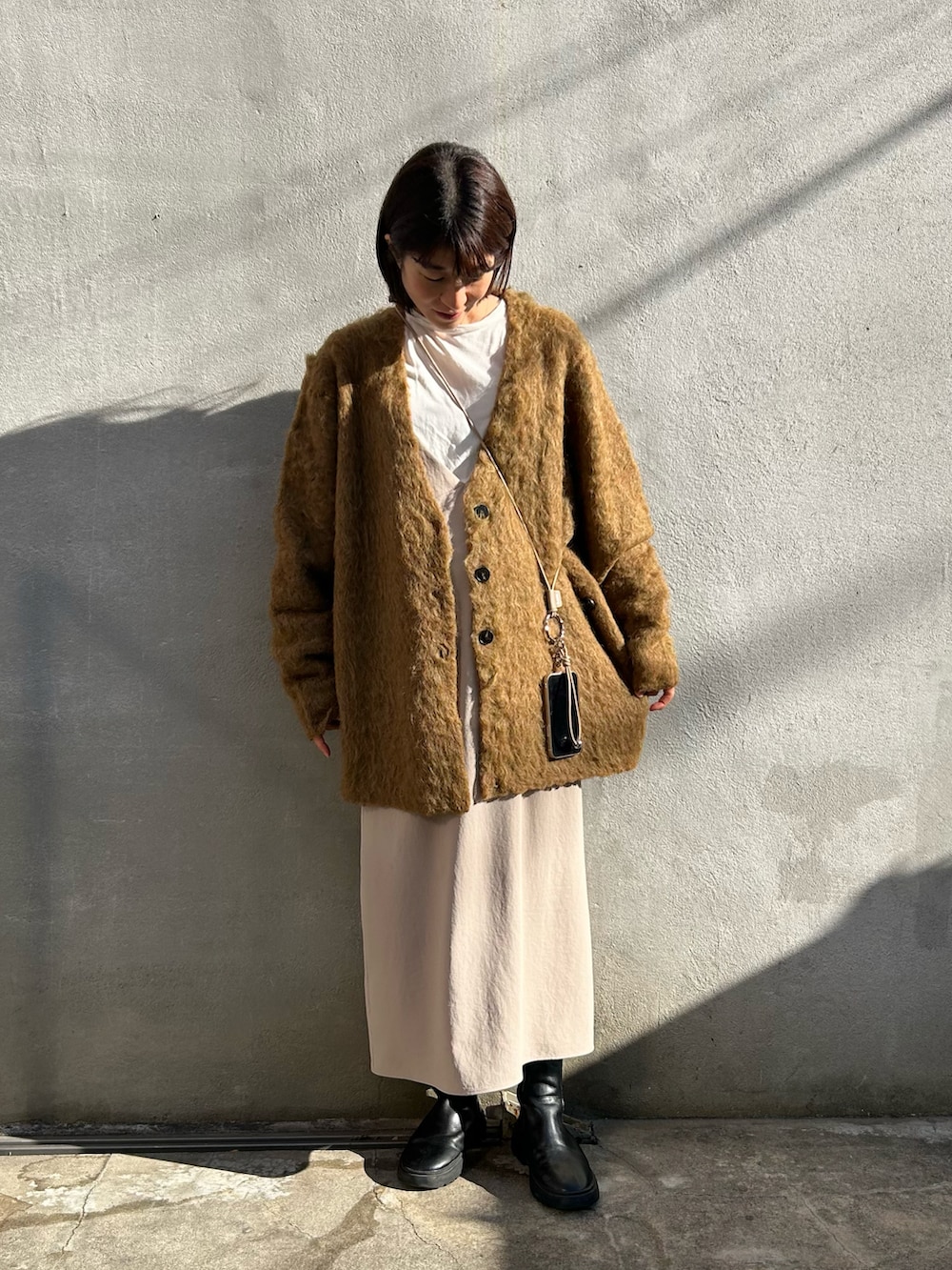 ブラック系のブーツ、グリーン系のニット/セーター、ベージュ系のワンピース/ドレスを着用したレディースの冬コーディネートの4枚目の写真