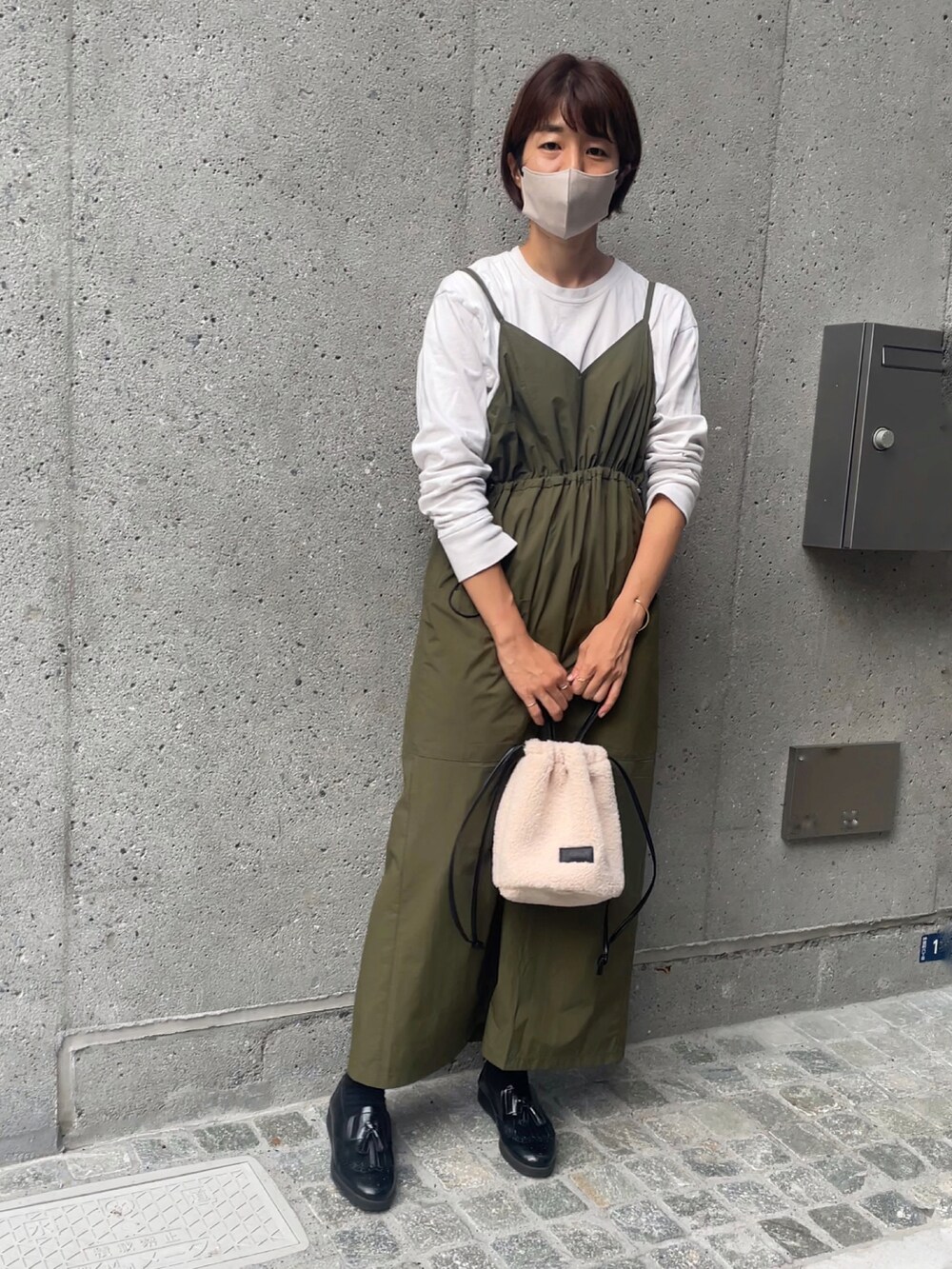 ホワイト系のショルダーバッグ、グリーン系のワンピース、ブラック系のローファーを着用したレディースの秋コーディネートの2枚目の写真