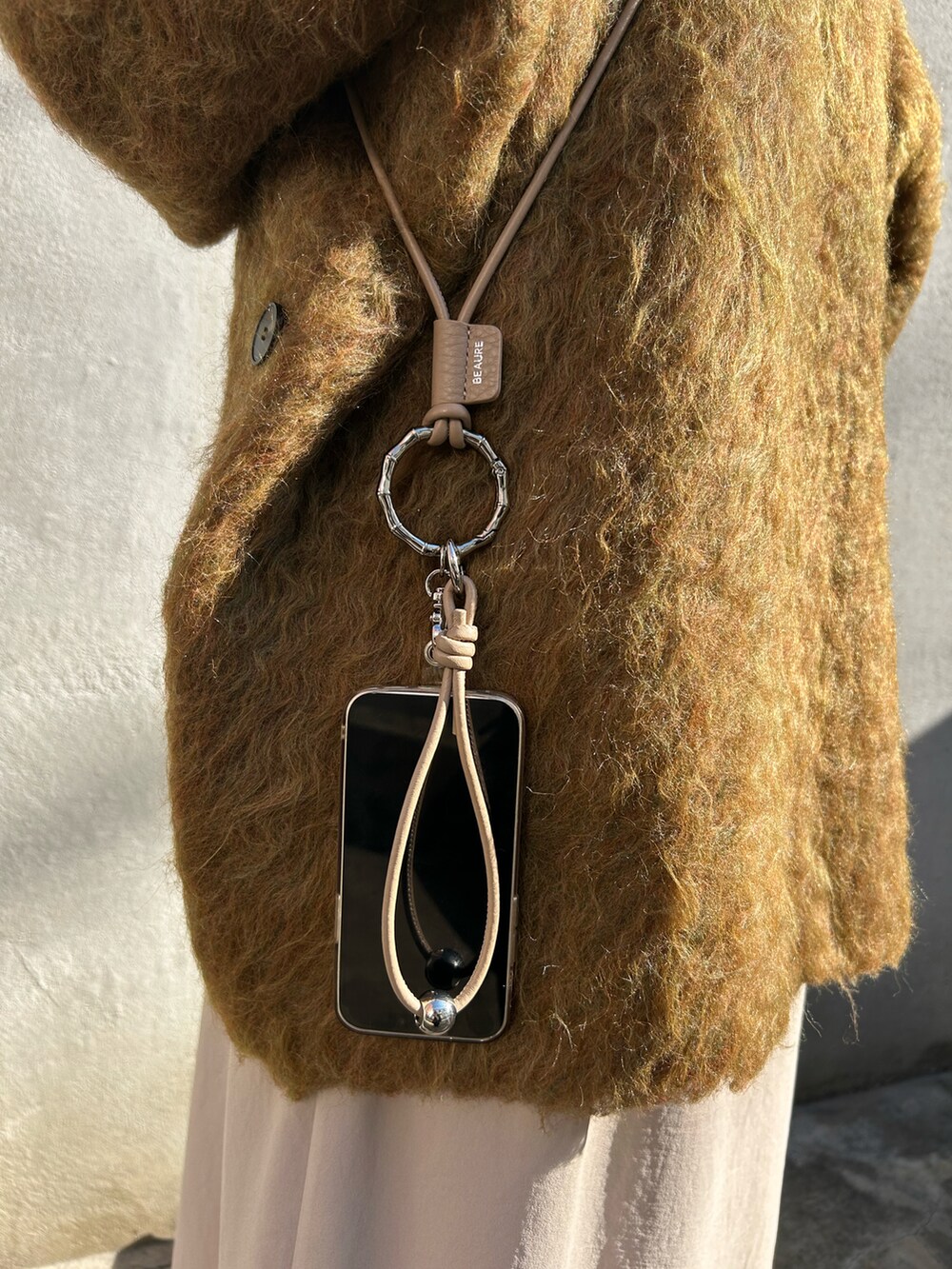 ブラック系のブーツ、グリーン系のニット/セーター、ベージュ系のワンピース/ドレスを着用したレディースの冬コーディネートの2枚目の写真