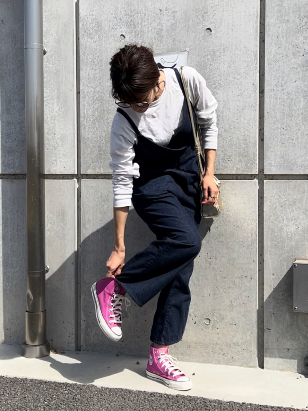 ゴールド系のショルダーバッグ、ピンク系のスニーカー、ブルー系のサロペット/オーバーオールを着用したレディースの春コーディネートの2枚目の写真