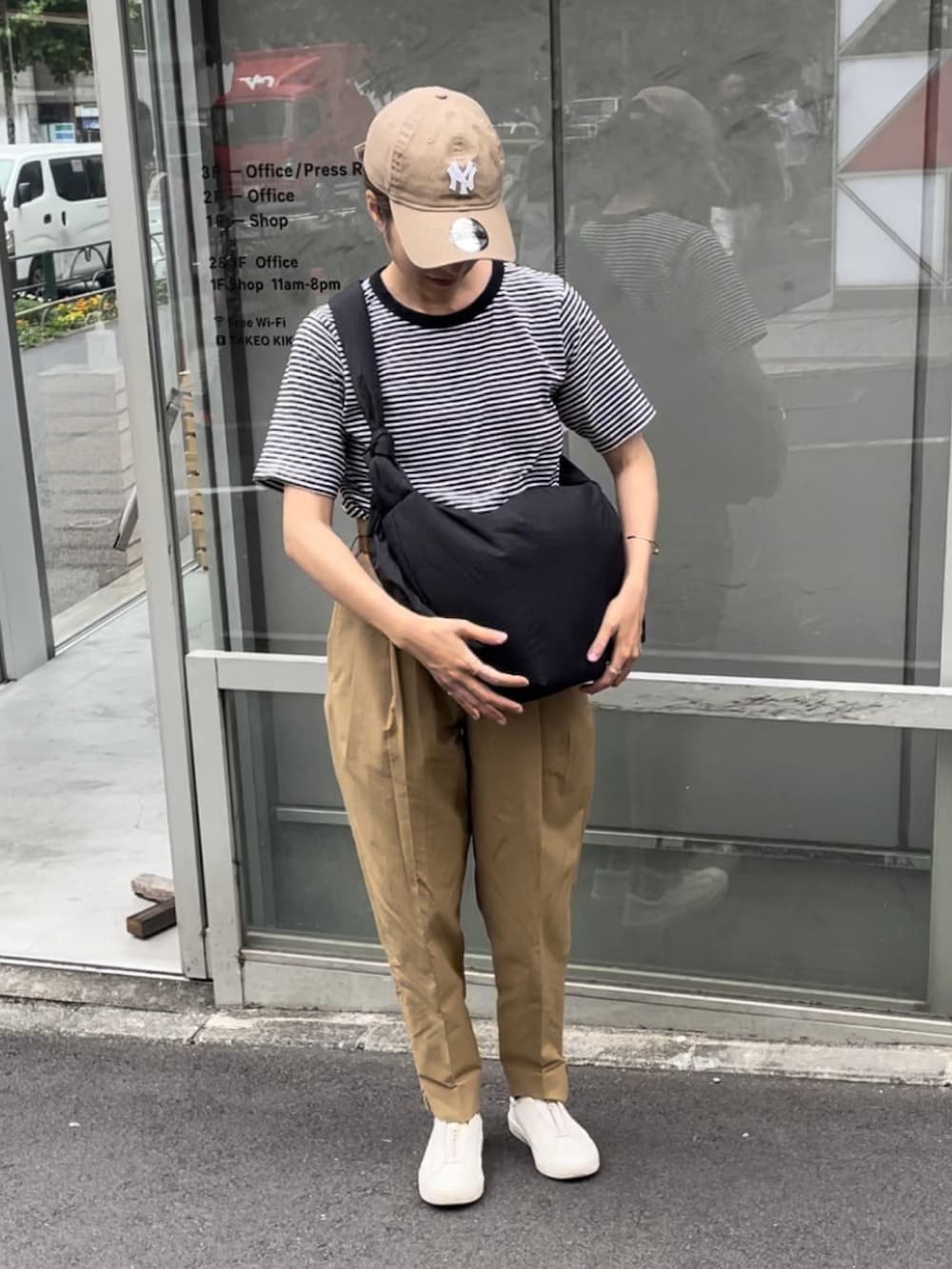 ブラック系のショルダーバッグ、ブラック系のTシャツ/カットソー、ベージュ系のチノパンツを着用したレディースの夏コーディネートの4枚目の写真