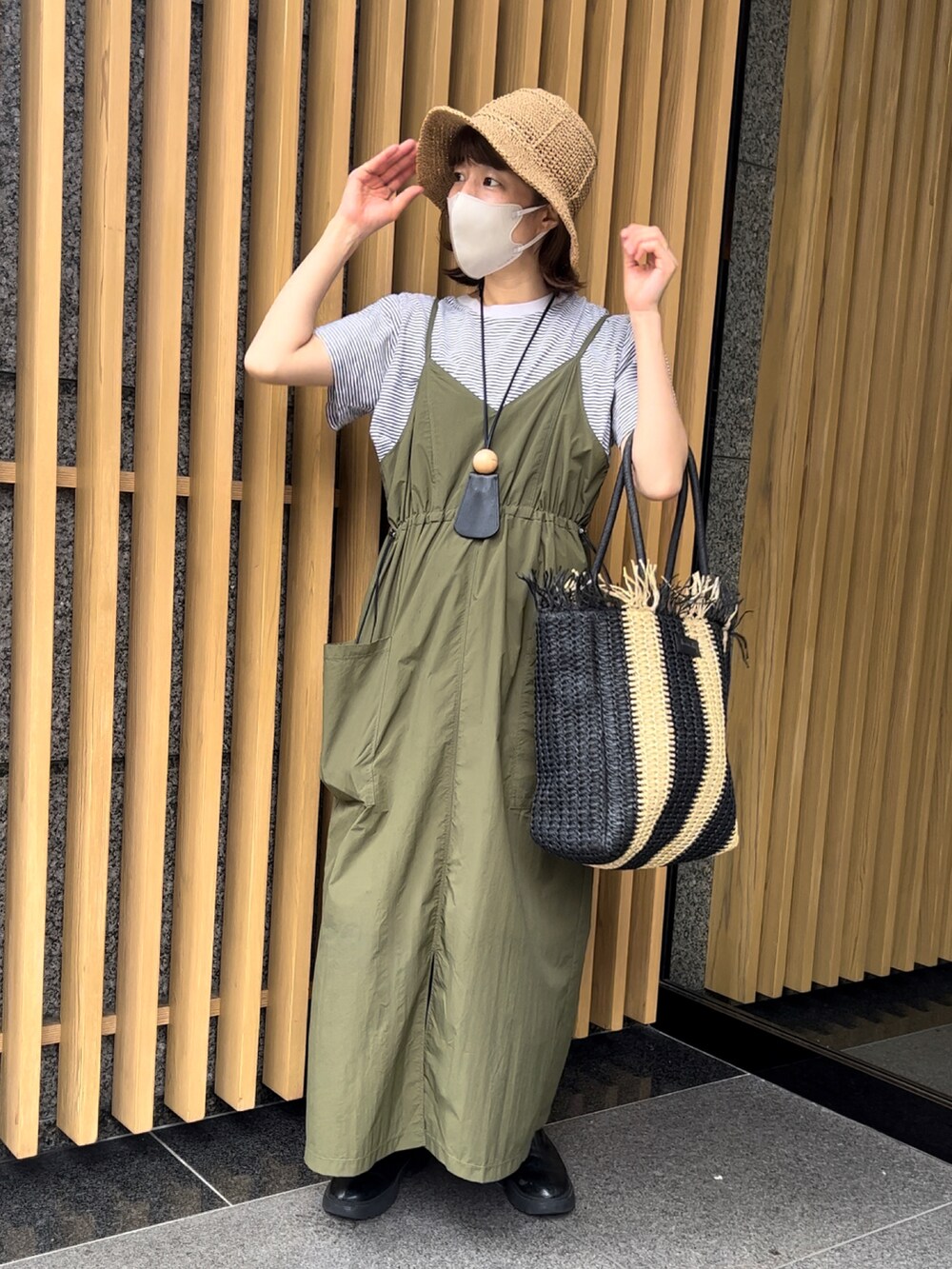 ブラック系のトートバッグ、グリーン系のワンピース、ブラック系のブーツを着用したレディースの春コーディネートの2枚目の写真