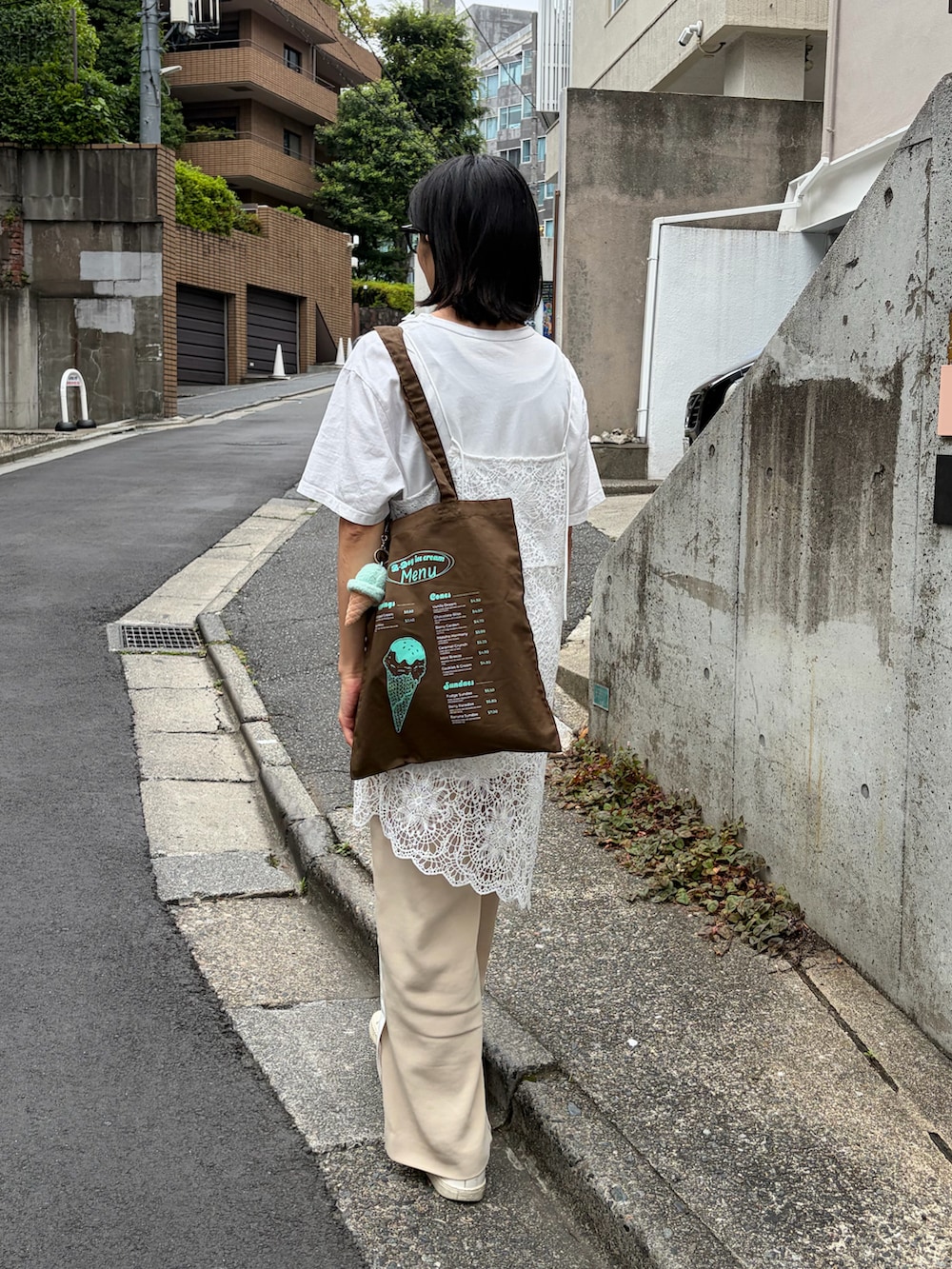 ブラウン系のトートバッグ、ホワイト系のTシャツ/カットソー、ベージュ系のキャップを着用したレディースの夏コーディネートの2枚目の写真