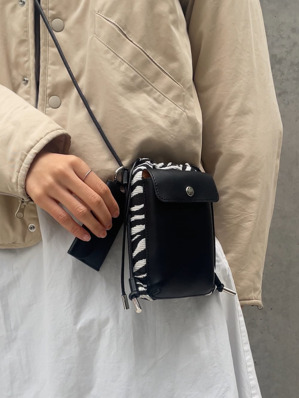 ホワイト系のジャケット/アウター、ホワイト系のワンピース、ブラック系のブーツを着用したレディースの冬コーディネートの2枚目の写真