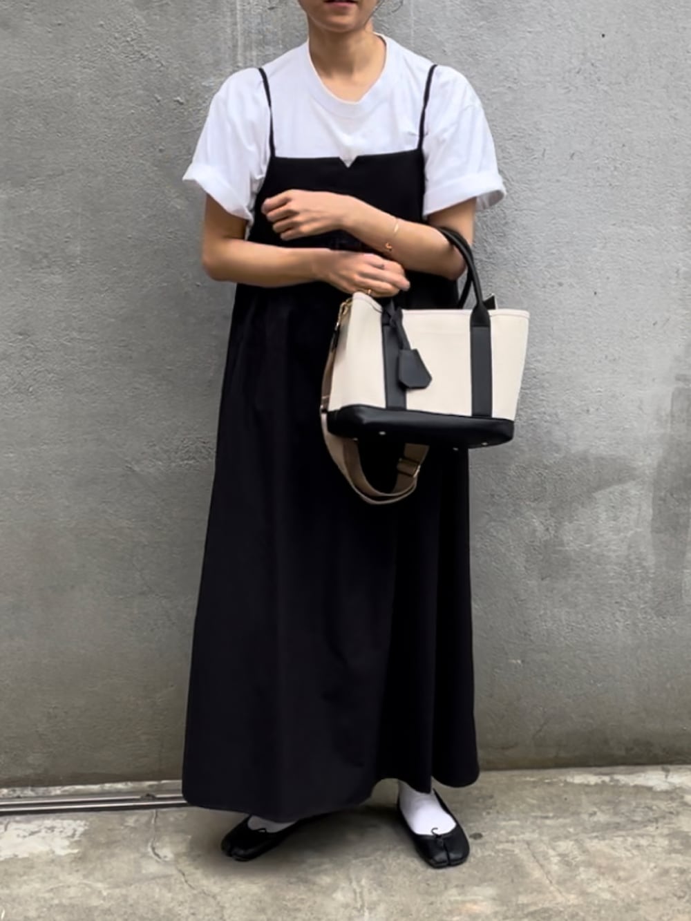 ブラック系のトートバッグ、ホワイト系のTシャツ/カットソー、ブラック系のワンピースを着用したレディースの春コーディネートの2枚目の写真