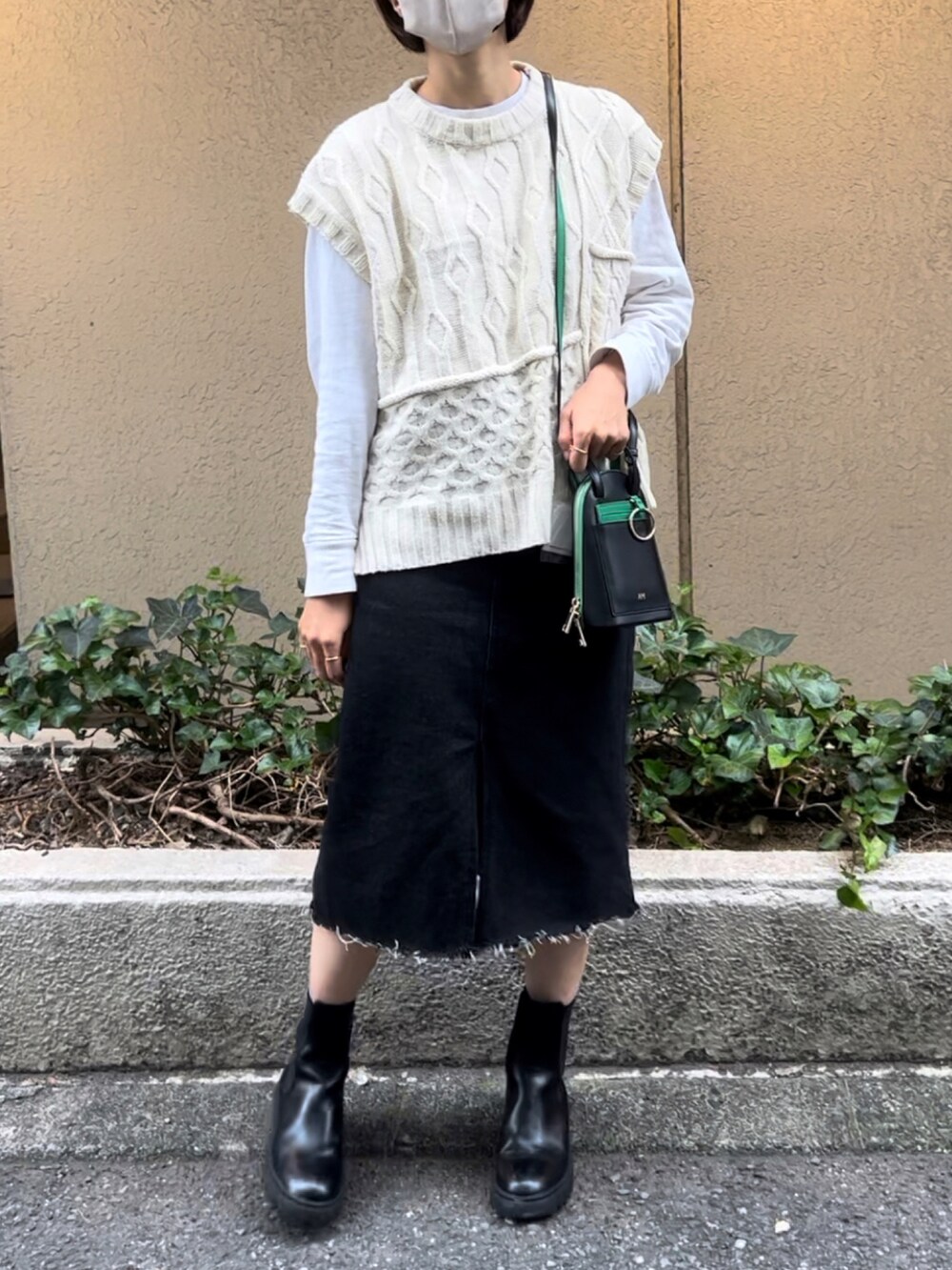 ブラック系のショルダーバッグ、ブラック系のデニムスカート、ブラック系のブーツを着用したレディースの秋コーディネートの2枚目の写真